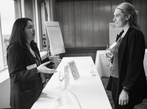 Black and white of people at event speaking across a table
