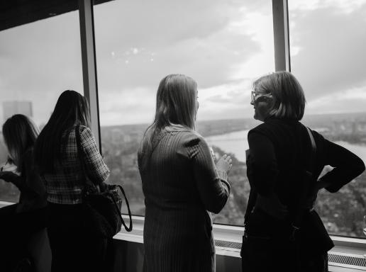 Black and white of people at event looking out window